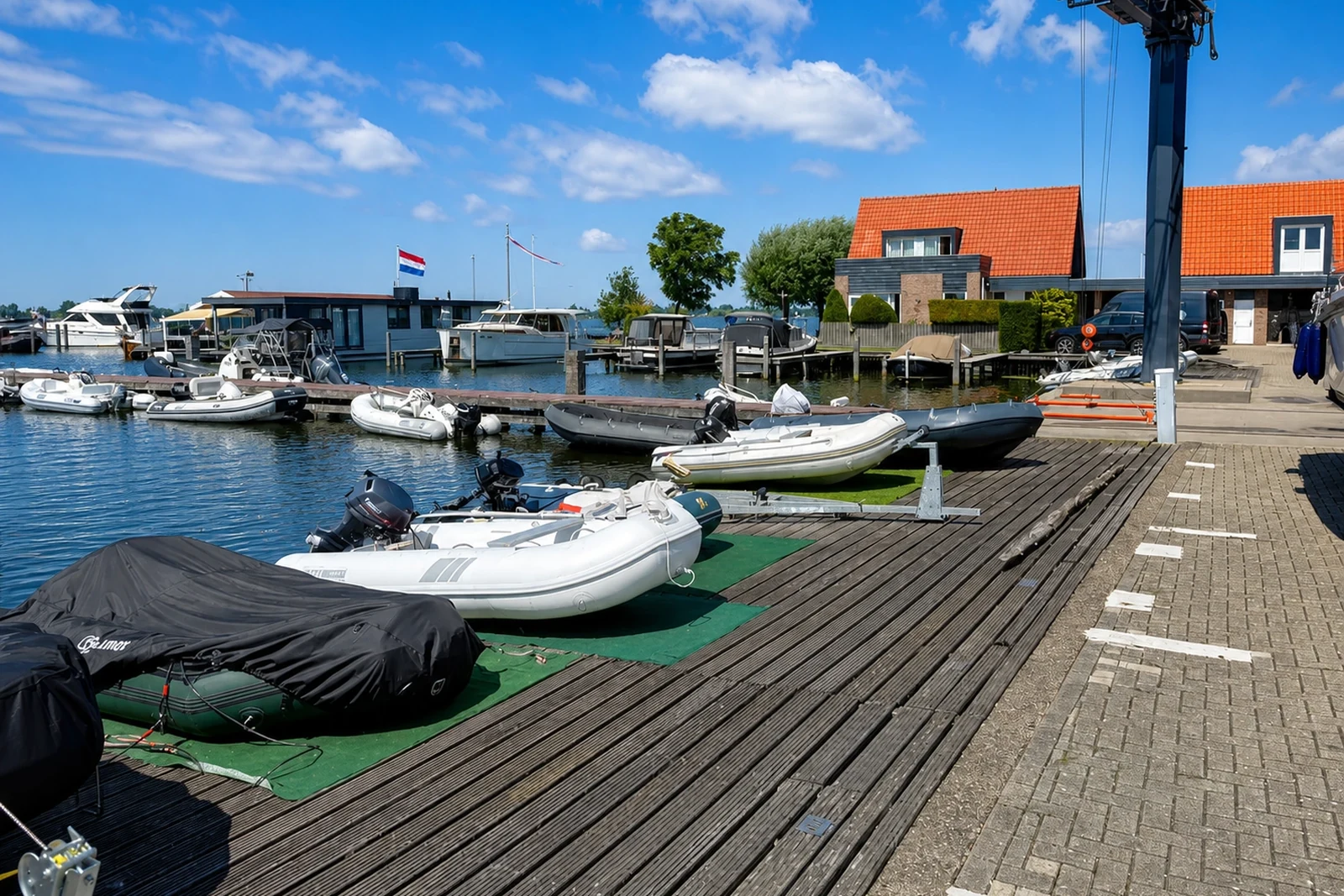 Botenkade met opgestelde rubberboten en een takelkraan aan het water